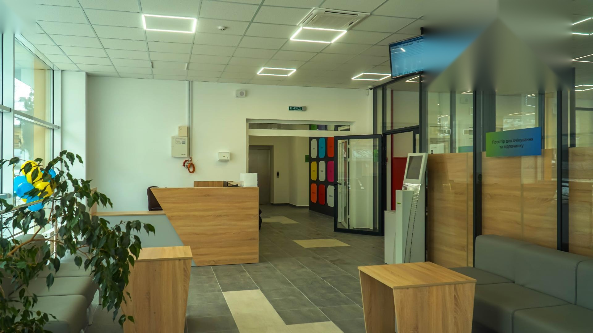 Reception area of the Drohobych Diia.Center with the QSolutions floor-standing registration kiosk on the right and a QS43 wall-mounted queue display above