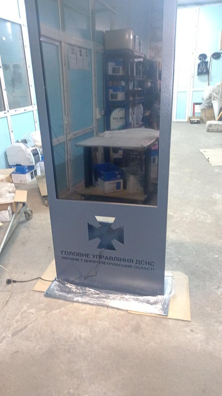 QS55 kiosk body during assembly in the QSolutions PRO workshop, showing the cut-out DSNS emblem before LED illumination is fitted