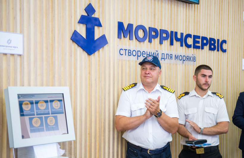 Ship captain in uniform standing near Morrichservice electronic queue notice