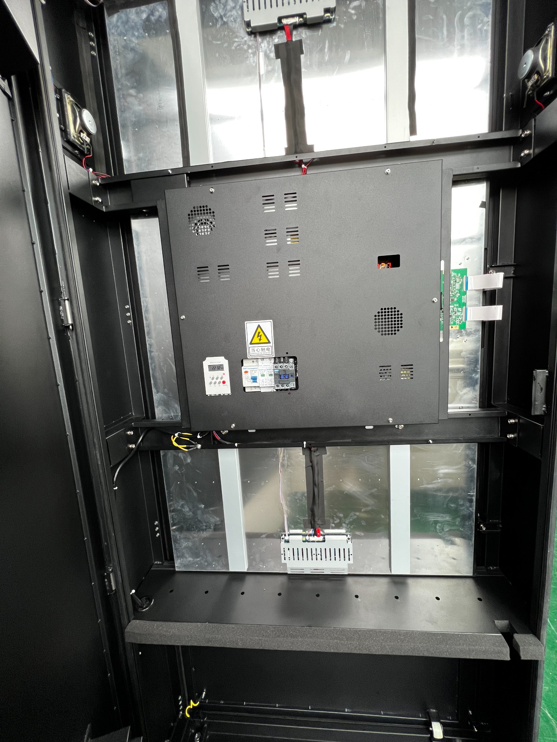 65″ Standard, straight-on view into the compartment: symmetrical airflow channels, two speakers, a control board, a shelf for the hardware